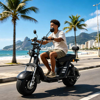 Jovem pilotando a scooter elétrica ZORYKEN M8-2000 preta pela avenida da praia no Rio de Janeiro, destacando o pneu sem câmara de 10 polegadas e o freio a disco hidráulico dianteiro, com o Morro Dois Irmãos ao fundo.