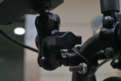 Detalhe do braço de fixação articulado com manopla de aperto preta em formato de borboleta, utilizado para ajustar a posição do suporte de celular no guidão.