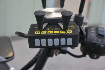 Detalhe frontal do painel do suporte de celular YL-B66, exibindo os botões emborrachados para ligar, pausar, avançar músicas e ajustar o volume do alto-falante Bluetooth.