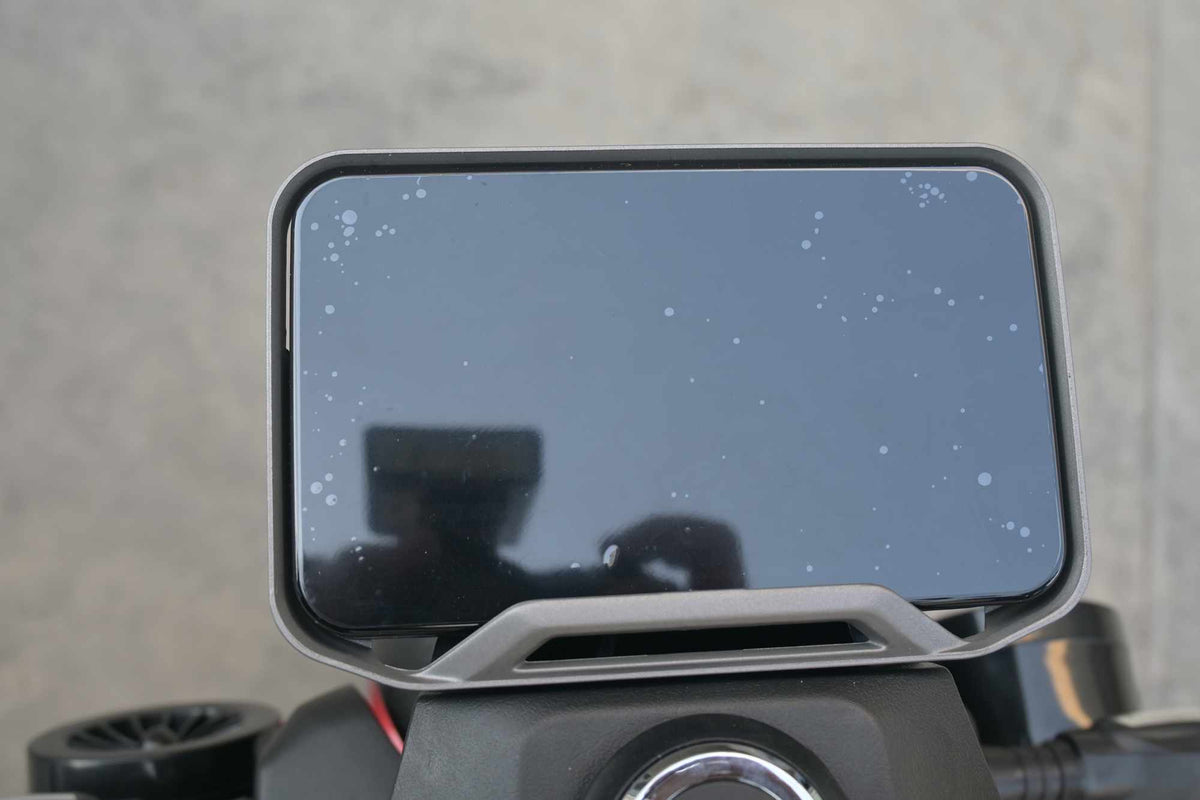 Visão frontal do painel de instrumentos amplo e digital da scooter elétrica com película protetora, fixado no guidão para exibição de velocidade e status.