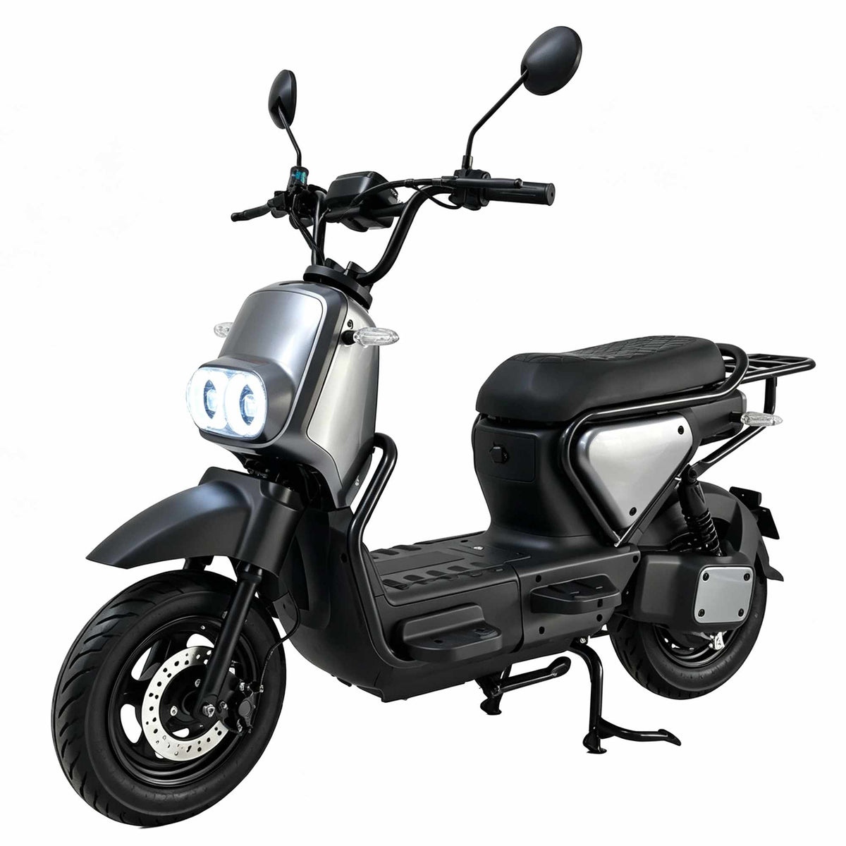 Visão de três quartos da scooter elétrica ZORYKEN Z5 na cor prata com os dois faróis dianteiros de LED acesos. Destacam-se o freio a disco ventilado na roda dianteira, os piscas laterais transparentes, as proteções tubulares pretas nas laterais e o descanso duplo acionado.